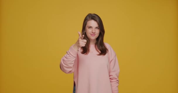 Hey you, choice gesture. Pretty young caucasian girl pointing at camera by fingers, picks candidate on yellow background - Záběry, video
