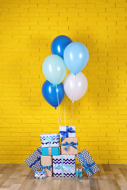 Many gift boxes and balloons near yellow brick wall - Photo, Image