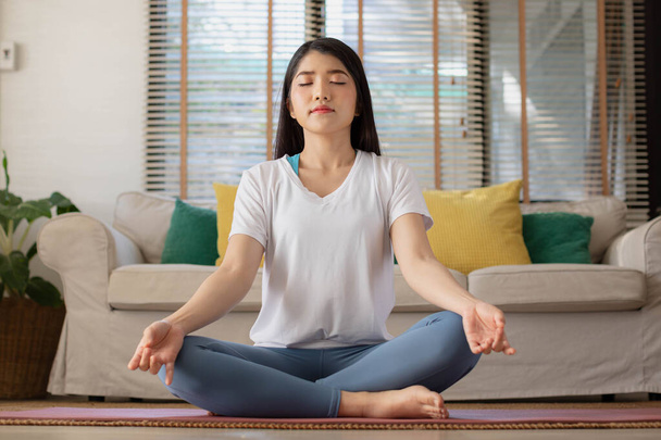 Asyalı bir kadınla sabah yogası, kolay bir pozisyonda oturmak, Sukhasana duruşu ve internette meditasyon yapmak.. - Fotoğraf, Görsel