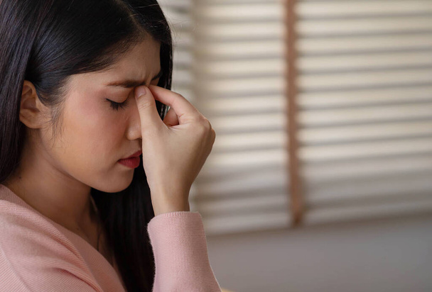 Asiatin massiert Nasenrücken-Schläfen. Gestresstes ungesundes Millennial Mischlingsmädchen fühlt sich müde und leidet an Migräne, Panikattacke. - Foto, Bild