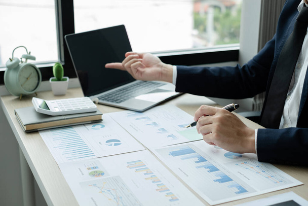 La mano del hombre de negocios se sienta en sus escritorios y calcula gráficos financieros que muestran los resultados de sus inversiones, planifica un proceso exitoso de crecimiento empresarial. - Foto, imagen