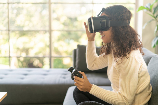 Latin nő használ virtuális valóság headset kanapén otthon - Fotó, kép