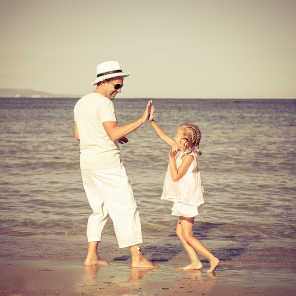 vader en dochter spelen op het strand - Foto, afbeelding
