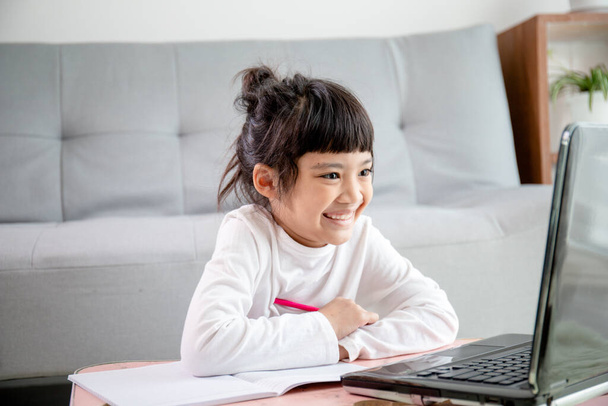 Asiatische Mädchen Student Online-Learning-Klasse studieren Online-Video-Anruf Zoom Lehrer, Glückliche Mädchen lernen englische Sprache online mit Laptop zu Hause .New normal.Covid-19 coronavirus.Social Distancing.stay home - Foto, Bild