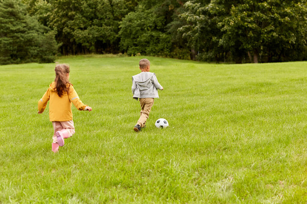 little children with ball playing soccer at park - Photo, image