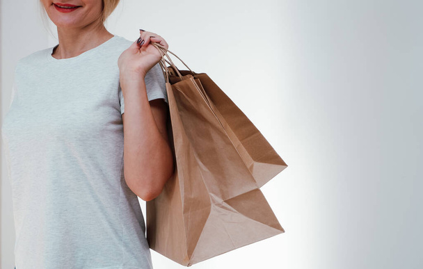 Emballage écologique. La fille tient des sacs en papier dans ses mains. Joyeux mignon femme méconnaissable est rentré à la maison du shopping avec des sacs en papier recyclé respectueux de l'environnement. - Photo, image