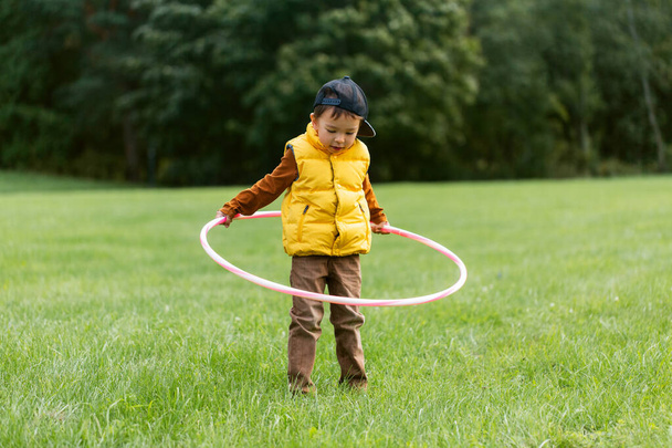 happy little boy playing with hula hoop at park - Foto, immagini