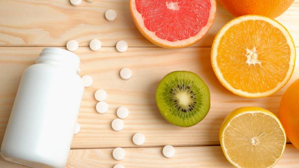Vitamins. Medical concept. Pharmacy or natural. White bottle with vitamins, scattered pills. Juicy citrus fruit slices. lemon. Orange. Grapefruit. - Valokuva, kuva