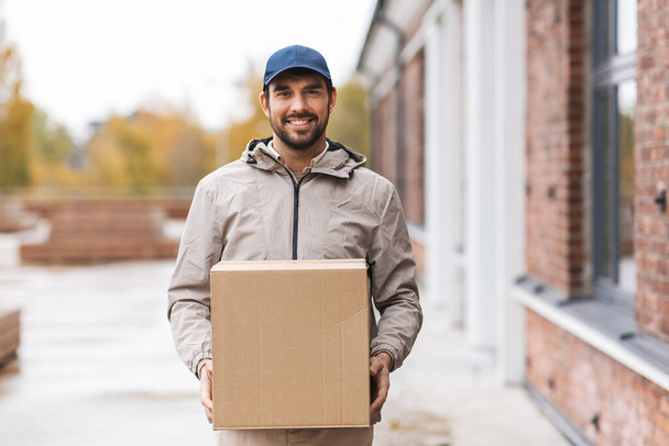 smiling delivery man with parcel box - Фото, изображение