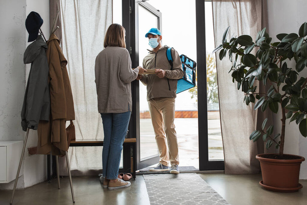 food delivery man in mask giving order to customer - Foto, Bild