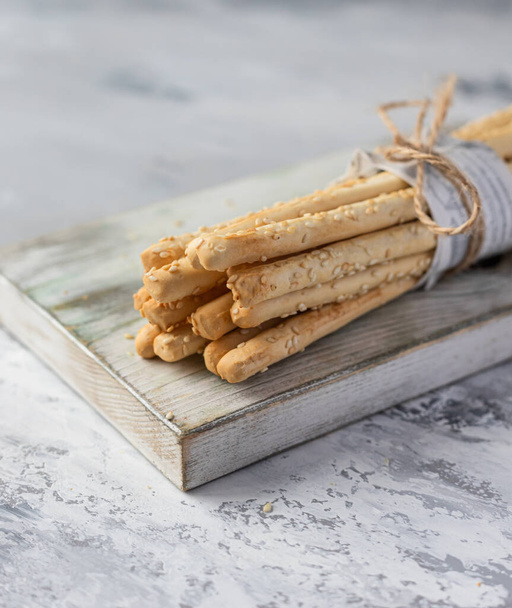 Italian grissini or salted breadsticks on a light stone background. Fresh italian snack with sesame seeds. - Valokuva, kuva