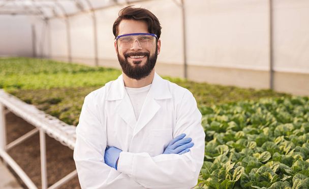 Cheerful man in eyeglasses standing in greenhouse - Photo, image