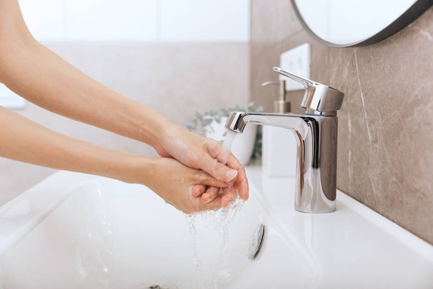 Washing hands under the flowing water tap. Washing hands rubbing with soap for corona virus prevention, hygiene to stop spreading corona virus in or public wash room. Hygiene concept hand detail - 写真・画像