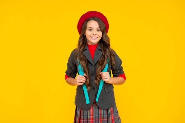 cheerful kid in school uniform with beret and backpack on yellow background, pupil - Valokuva, kuva