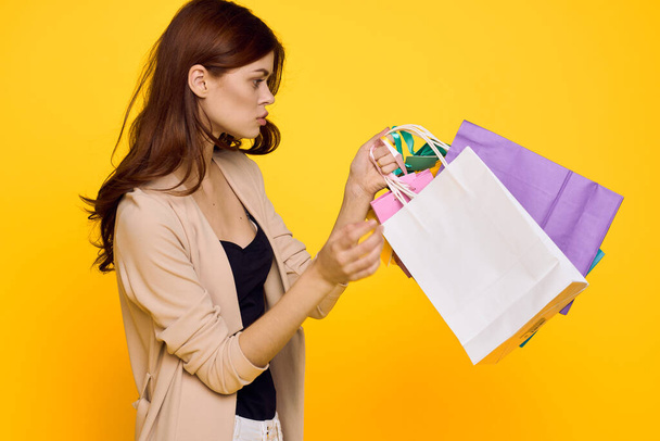glamorous woman multicolored packs emotions shopping fashion yellow background - Zdjęcie, obraz