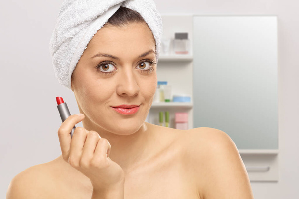Young woman holding a red lipstick in a bathroom - Φωτογραφία, εικόνα