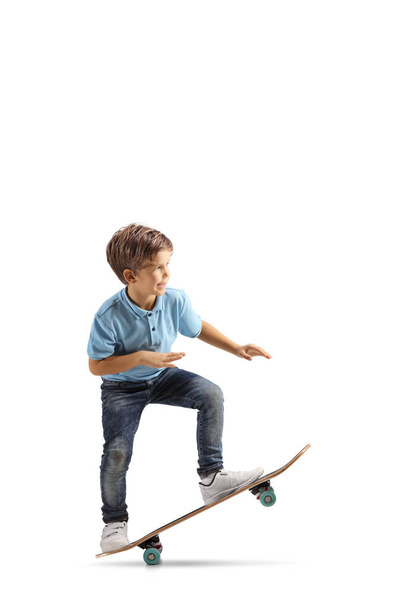 Kleiner Junge macht einen Trick mit einem Skateboard auf weißem Hintergrund - Foto, Bild