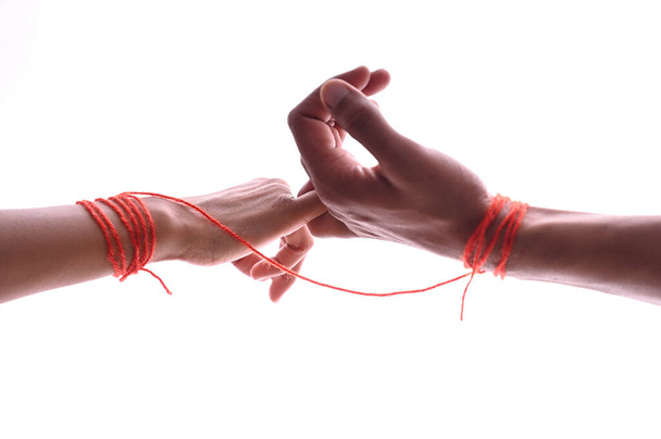 A male and female hands wrapped in red thread isolated on white, concept of desire and love - 写真・画像
