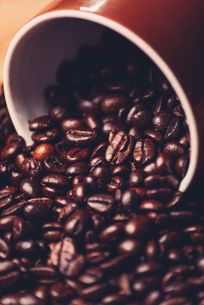 The coffee beans scattered on a table near the mug - Fotó, kép