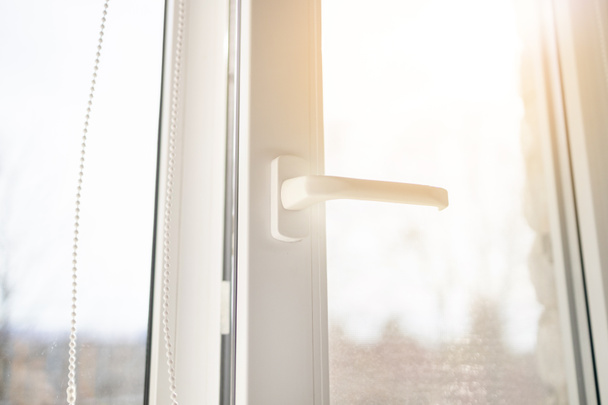 Weißes Kunststoff-PVC-Fenster mit Waldhintergrund zu Hause. Sonnenstrahl durch Glas - Foto, Bild