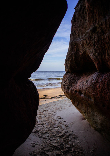 The sandy beach and the ocean in the background viewed from a cave - Foto, Imagem