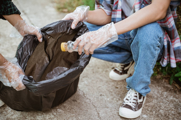 hand picking up plastic waste and put in the trash bag - Fotografie, Obrázek