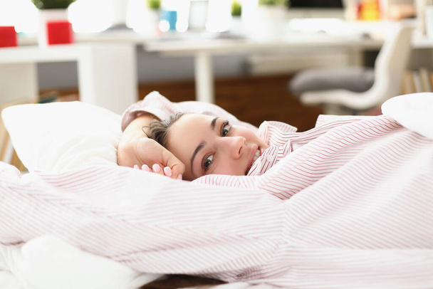 Mutlu genç bir kadın, rahat bir ev yatağında keyifle uyanıyor. - Fotoğraf, Görsel