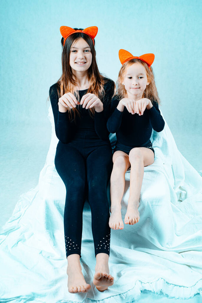 Two little smiling girl with cat ears on her head posing on a white background. Children portray little kittens. Children are isolated on a white background. - Fotografie, Obrázek