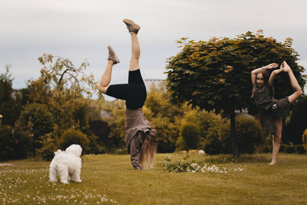 Young sportive girl shows gymnastic exercises outdoors. Sport and healthy lifestyle concept. The girl is in her arms. - Photo, Image