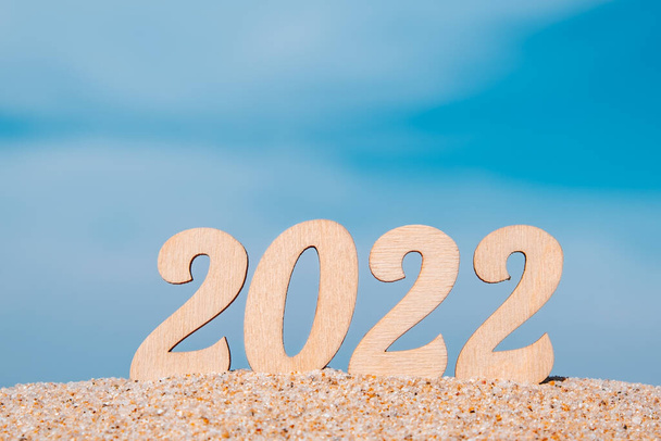 New Year numbers 2022 on sandy beach against the sky. Tourism, adventure and travel concept. Creative Christmas card. Selective focus. Copy space. - Photo, Image