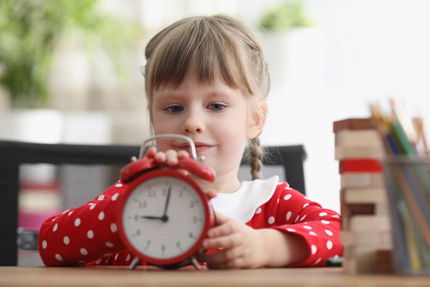 かわいい子供は時間を理解し、赤いレトロ時計で遊ぶ方法を学びます - 写真・画像