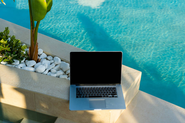 a laptop on the deckchair in swimming pool - Photo, Image
