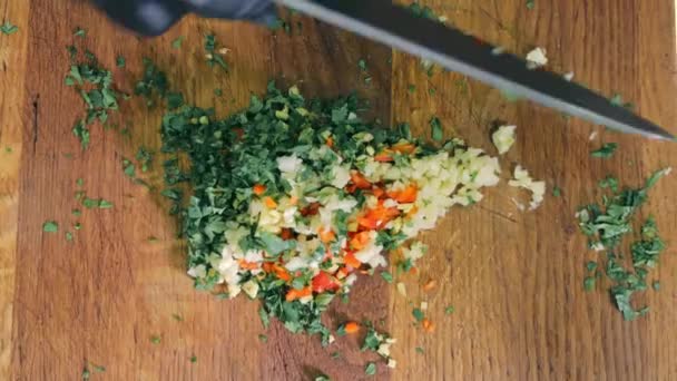 Mescolare le verdure appena tritate e insalata o marinata ingredienti con un coltello. Il cuoco mescola verdi, prezzemolo, pepe rosso e aglio. - Filmati, video