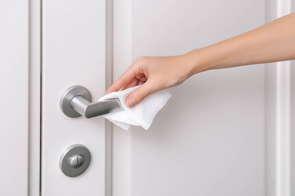 Cleaning door handles with an antiseptic wet wipe and gloves. Woman hand using towel for cleaning home room door link. Sanitize surfaces prevention in hospital and public spaces against corona virus - Fotoğraf, Görsel