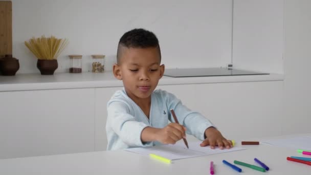 Chico afroamericano divertido dibujando con lápices de colores en casa - Metraje, vídeo