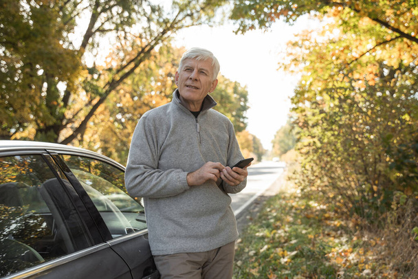 Man looking away with pensive expression while standing near his car at the forest - Photo, image