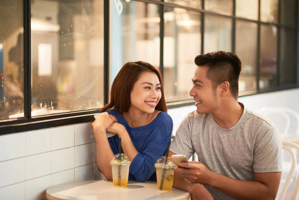 Asian Couple Talking In Modern Cafe - Foto, afbeelding
