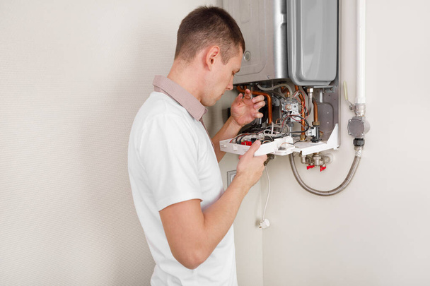 Plumber attaches Trying To Fix the Problem with the Residential Heating Equipment. Repair of a gas boiler - Foto, afbeelding