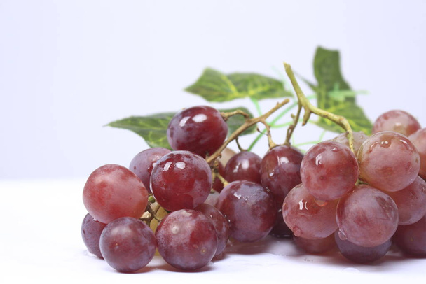 Druiven zijn de vrucht van een houtachtige wijnstok. Druiven kunnen rauw gegeten worden, of gebruikt worden voor het maken van wijn, sap en jam. Druiven zijn er in verschillende kleuren; rood, paars, wit. Fokus vervaging. - Foto, afbeelding