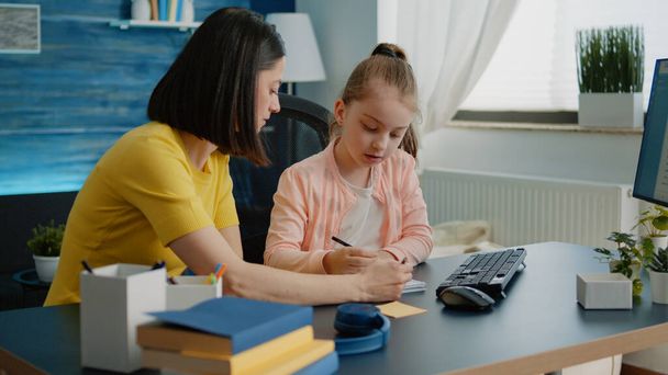 Мать и дочь делают домашнюю работу вместе для онлайн урока - Фото, изображение