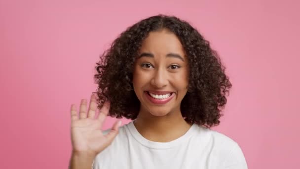 Vrolijke zwarte jonge dame zwaaien hand over roze studio achtergrond - Video