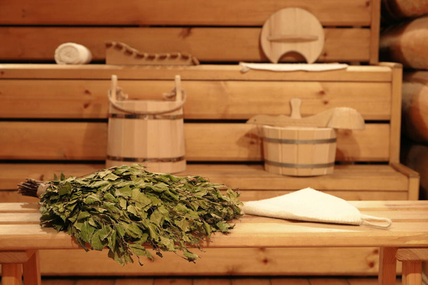 Koivun luuta puinen penkki ja perinteinen sauna tarvikkeet sisätilojen venäläisessä kylvyssä.  - Valokuva, kuva
