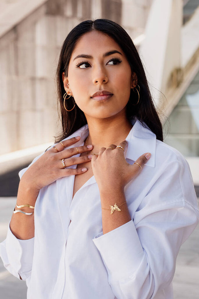 Latin woman posing in the street with gold jewelry. Elegant business girl, - Zdjęcie, obraz