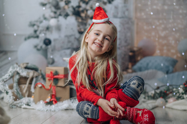 Schöne blonde Mädchen mit Weihnachtsmütze und rotem Pullover. Design von Weihnachtsgrußkarten - Foto, Bild