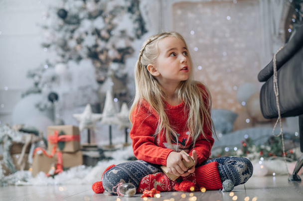 Merry Christmas and Happy Holidays! The morning before Xmas. Portrait of little happy girl wearing Christmas jumper - 写真・画像