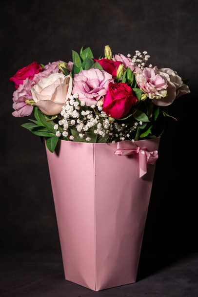 A bouquet of flowers in a box. Gift pink box with flowers on a black background. - Fotoğraf, Görsel