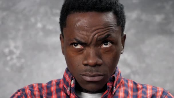Close up face adulto afro-americano homem olhando câmera, no fundo cinza parede - Filmagem, Vídeo