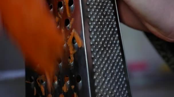 Großaufnahme einer Frauenhände, die Möhren auf einer Reibe reibt. Hausfrau raspelt Möhre in Küche. - Filmmaterial, Video