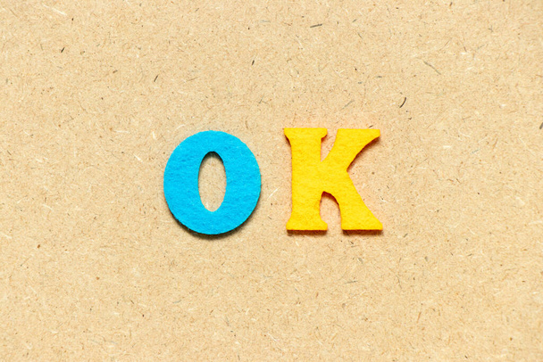 Color cloth alphabet letter in word OK on wood background - Foto, afbeelding