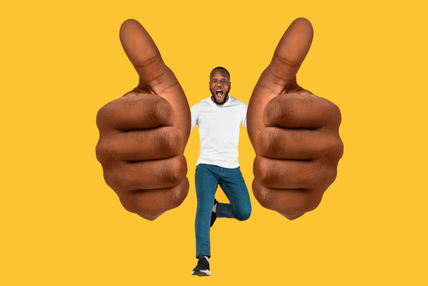 Συναισθηματικός μαύρος τύπος που δείχνει τεράστια ups αντίχειρα πάνω από κίτρινο φόντο - Φωτογραφία, εικόνα
